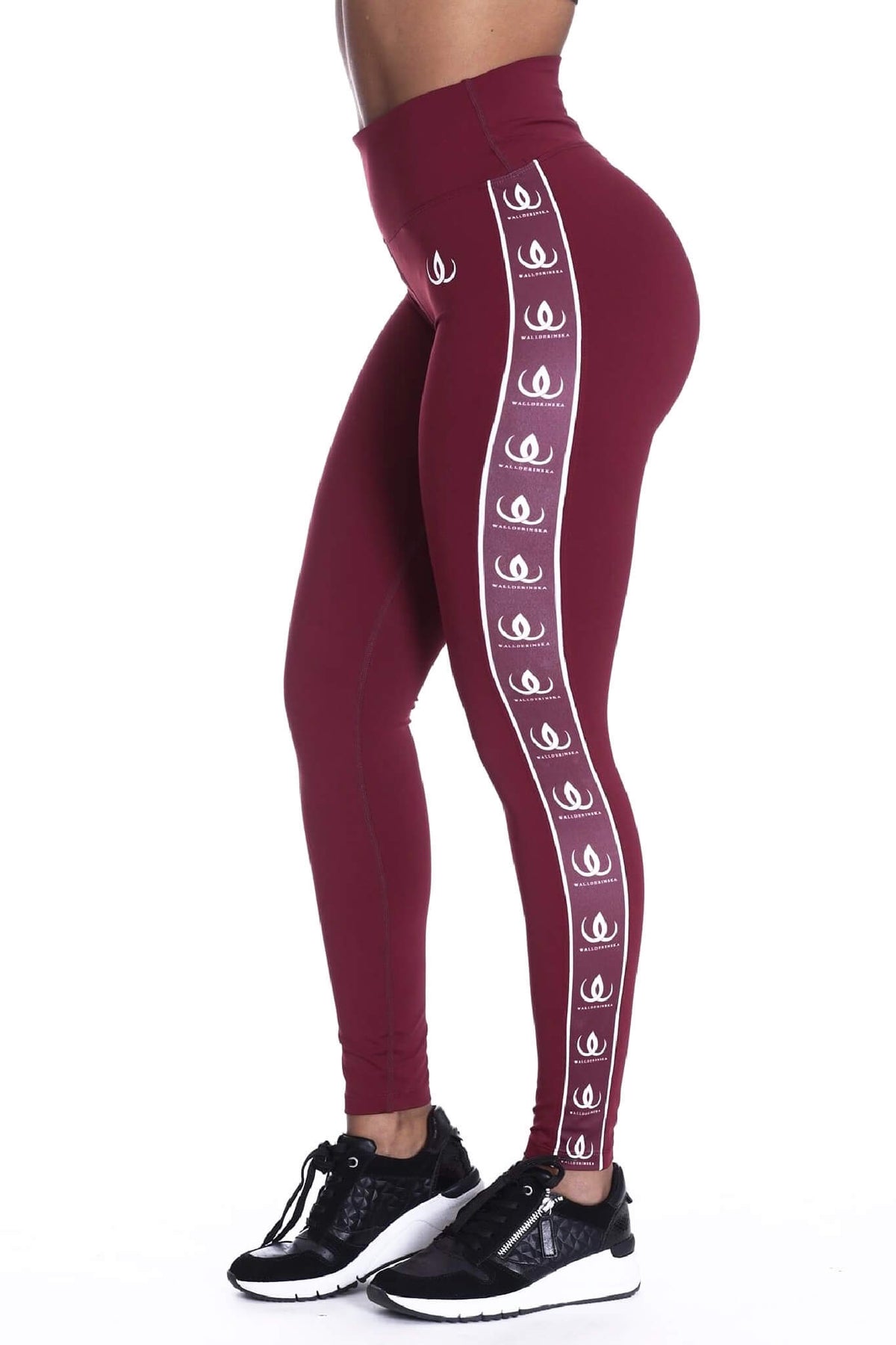 Den høje talje på de vinrøde tights, med hvidt logobånd langs siden og sorte sko nederst.