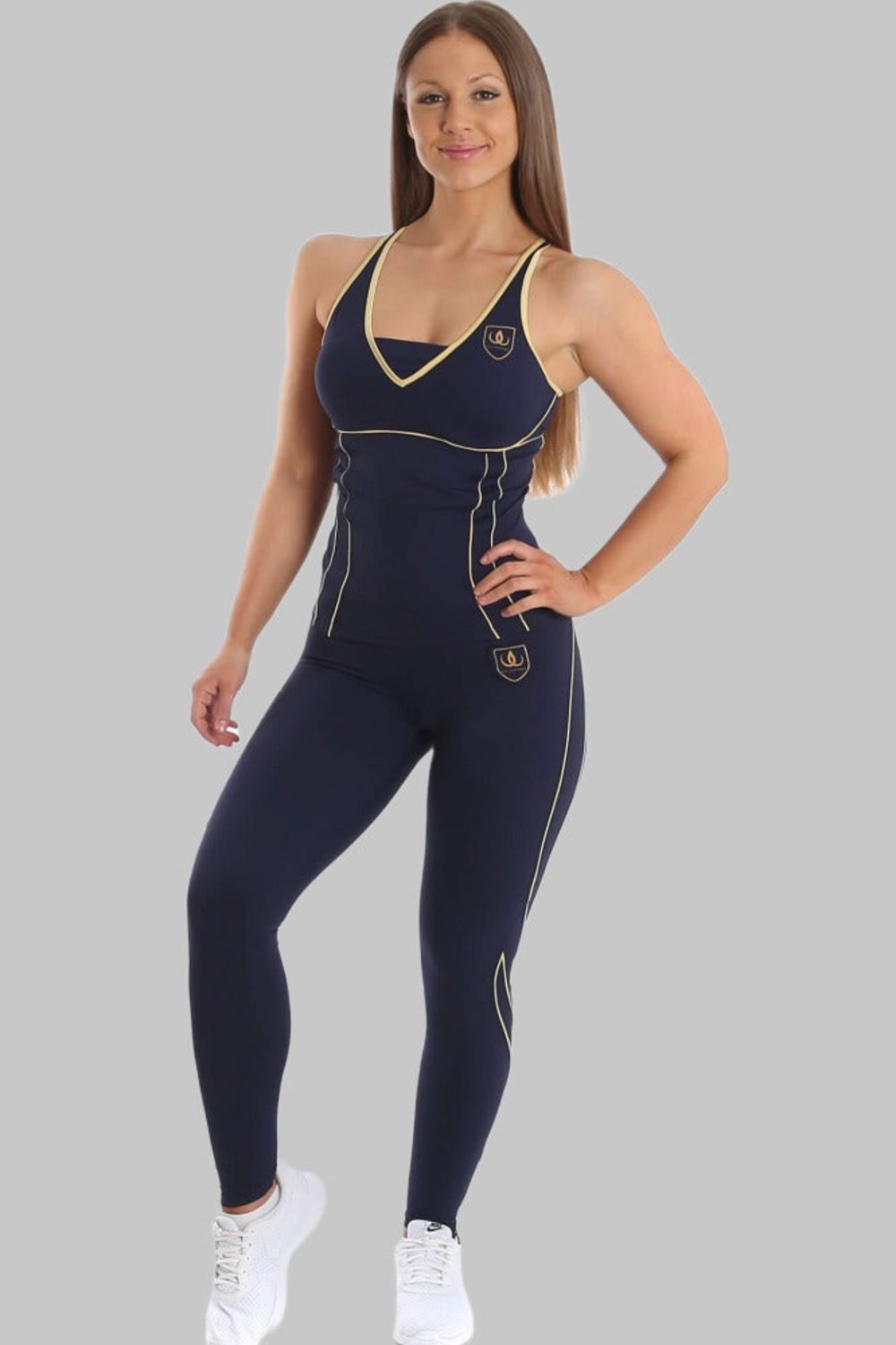 Modellen står i marineblå træningstop og marineblå tights med guldlinjer, til hvide sneakers.