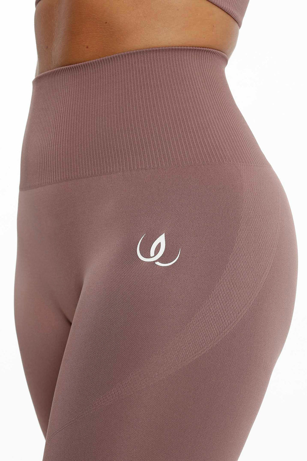 Den ribbede linning og det hvide logo på hoften, stoffet i en dæmpet rosabrun tone.