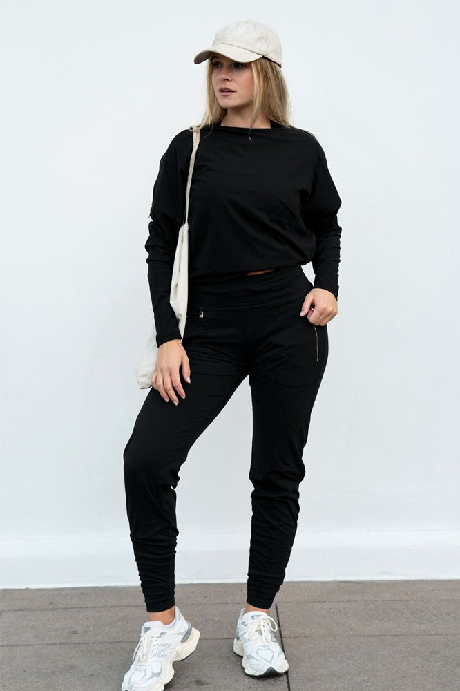Kasket og mulepose til bukserne og en kort sort sweater. Modellen står stille.