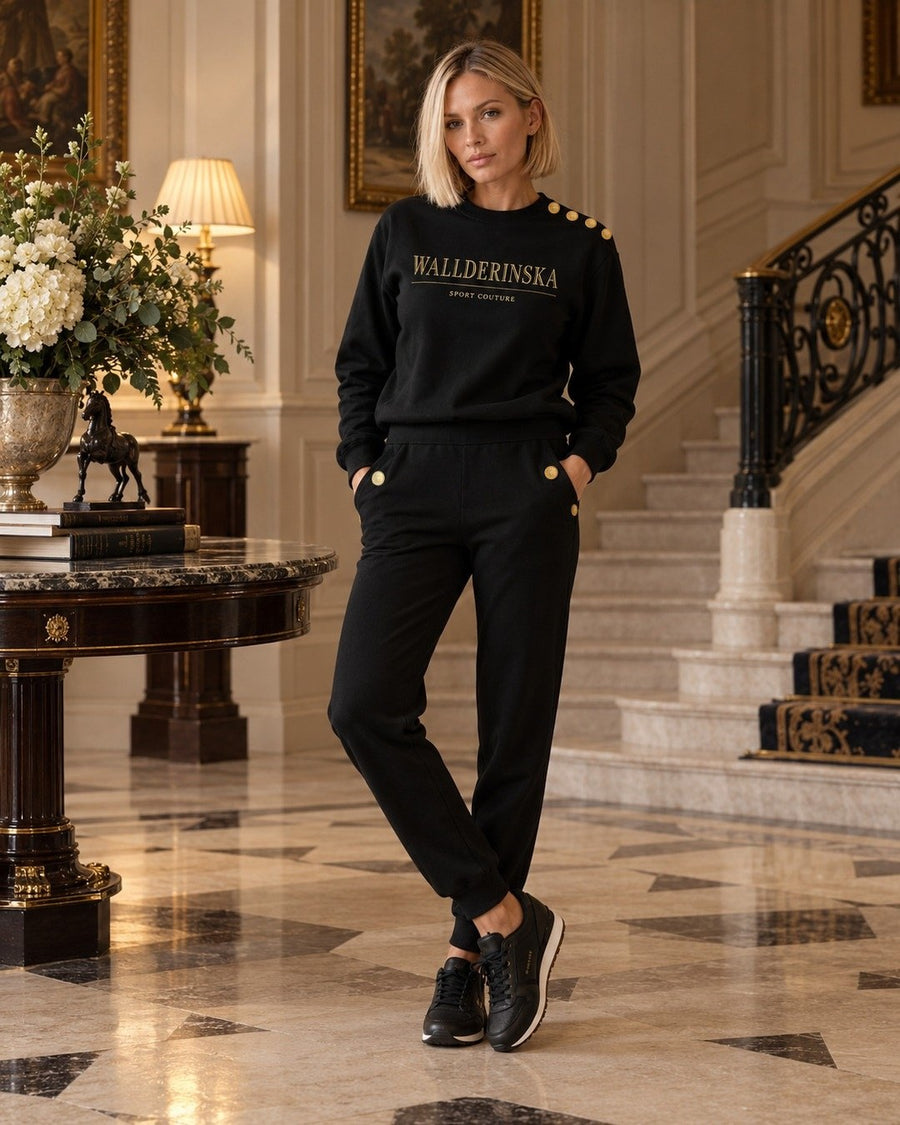 Edge Gold Button Sweater og Edge Gold Button Bukser i en hall med marmorgulv.